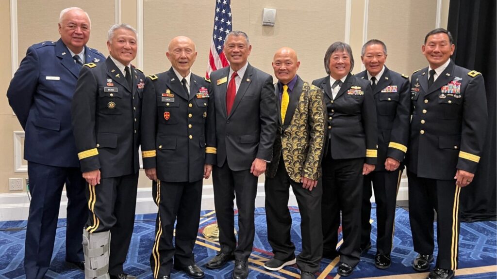 Military officials posing for a group photo with Ed Gor in the gold jacket