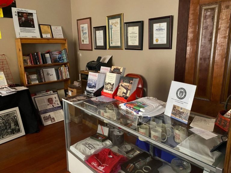Photos of the CHSSC Bookstore with small book case, framed proclamations and display case with t-shirts, cups and other items for sale