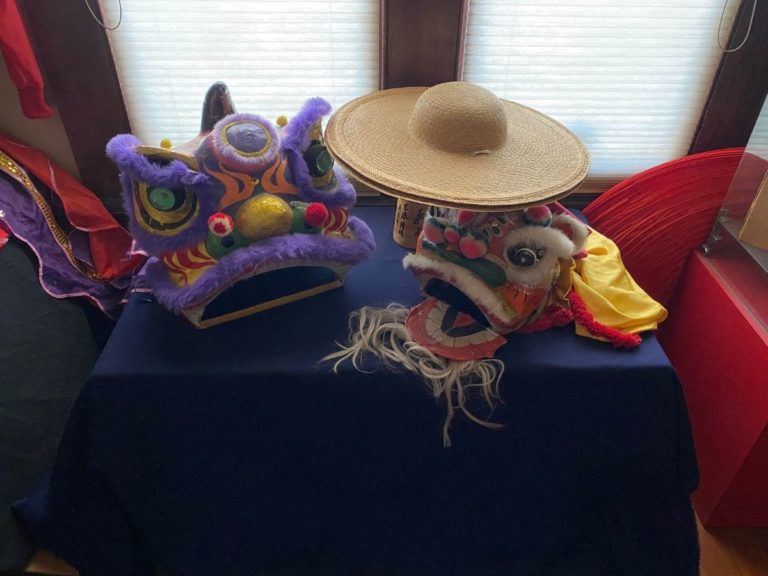 Photos of the CHSSC Bookstore showing a display table with two Chinese lion heads and hat
