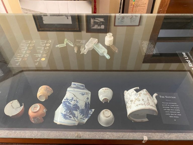 Photo of front display room showing detailed view of the artifacts in the display case with tea service