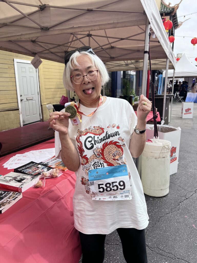 Board member Cindy Fong shows off her medal at the Firecracker Run