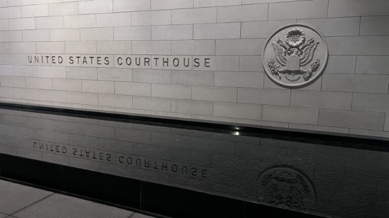 Outside photo of the courthouse building sign with reflecting pool of water.