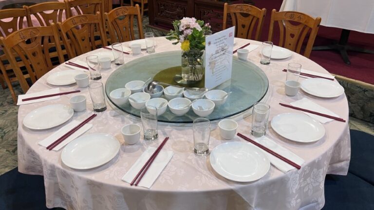 One of the four table settings with flower centerpiece and menu for the dinner.