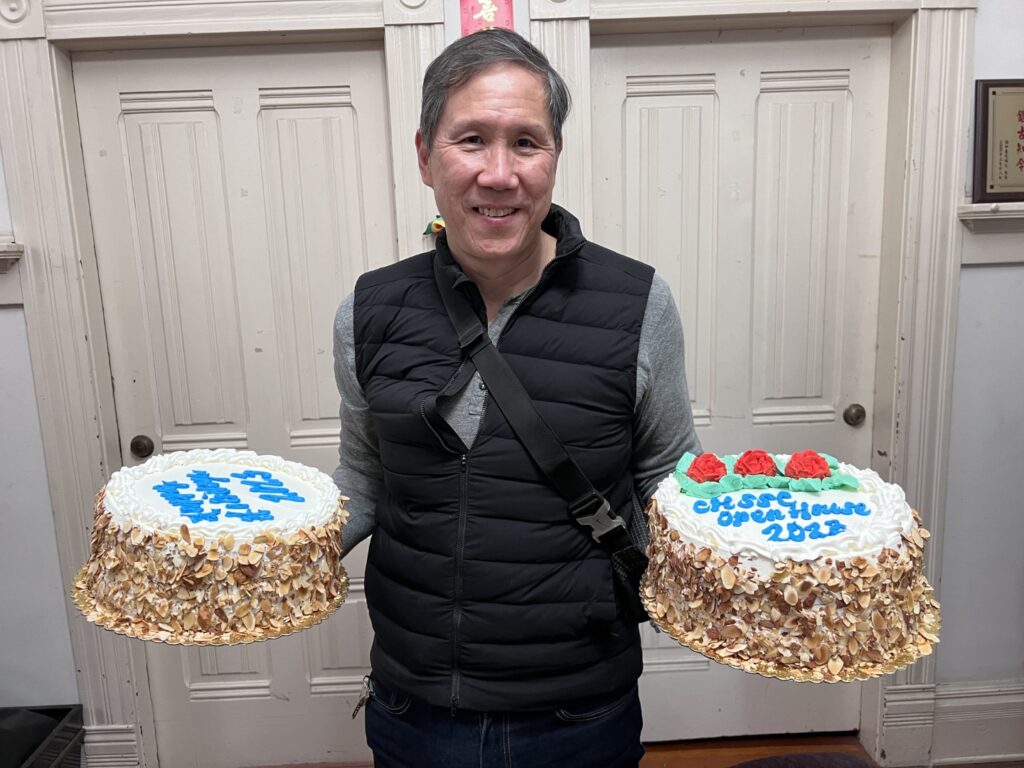 Board member Robert Chong holding two strawberry cakes donated by Phoenix Bakery