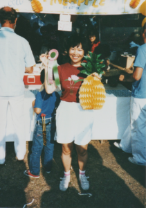 Image from the Lotus Festival in Echo Park, young Chinese woman holding an award ribbon and a paper pineapple