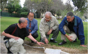 Group of four men discussing headstones used to line the driveway to the crematorium in Evergreen Cemetery